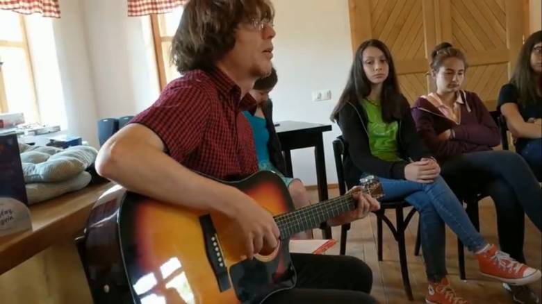 Gitárral, zenével hozza közelebb a gyerekekhez a verset – a képen éppen a Cimbora-táborban
